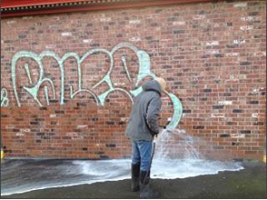 Pressure washing tech removing graffiti from a Eugene building